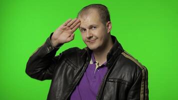 Rocker man saluting with hand and pretending to listen order. Guy biker on chroma key background video