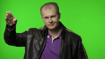 Rocker man saluting with hand and pretending to listen order. Guy biker on chroma key background video