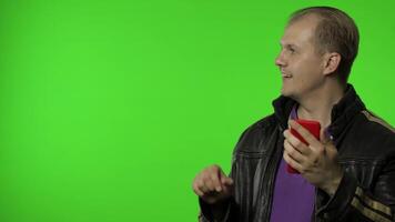 Rocker man showing side advertising area. Using smartphone, pointing at wall for your text, logo video