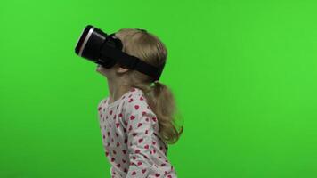 Child girl using VR headset helmet to play game. Watching virtual reality 3d 360 . Chroma key video