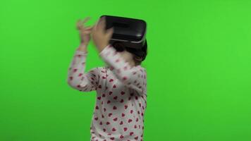 Child girl using VR app helmet to play simulation game. Watching virtual reality 3d video
