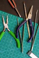 Overhead view on tools on a green cutting mat for crafting handmade jewelry things. photo