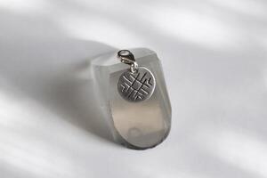 Silver round pendant with unique geometric grooved pattern. Handcraft precious item. photo