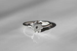 minimalista plata anillo con un en forma de flor ajuste en un blanco antecedentes. hecho a mano joyas. foto