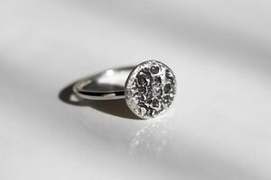 Silver ring with a rough textured moon surface on a white background. Handcraft precious item. Jewelry accessories. photo