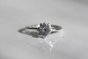 minimalista plata anillo con un en forma de flor ajuste en un blanco antecedentes. hecho a mano joyas. foto