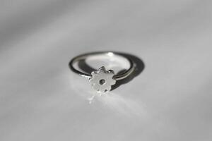 minimalista elegante plata anillo con un en forma de flor separar en un blanco brillante antecedentes. foto