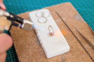 Detailed process of jewelry making with a torch on a white work surface in a creative studio. photo