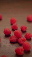 Delightful scene of fresh raspberries tumbling gracefully onto a rustic wooden surface video