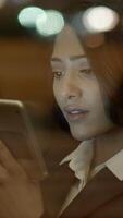 A woman is actively using her smartphone in a vibrant modern setting during the night, video