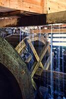 Old wooden waterwheel splashed by falling water. Picture from a watermill in Sweden photo