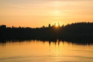 Sunset with warm colors on a Swedish lake in Smalland. Romantic evening atmosphere photo