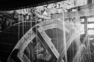 Old wooden waterwheel splashed by falling water. Picture from a watermill in Sweden photo