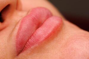 A close up of a womans lips after permanent makeup. The lips are well groomed with a soft pigment shade that is fully healed. photo