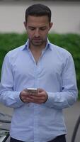 A man is using his smartphone while in an urban setting during daylight hours and is relaxed video