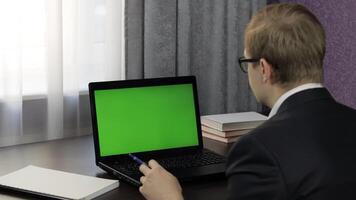 Man have call conference on laptop with green screen. Distance work online video