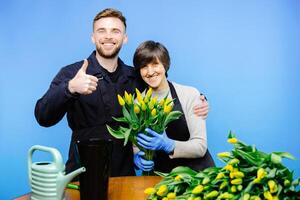 Flower shop. A young guy helps an older woman florist take care of flowers in a flower studio photo