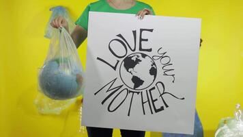 Unrecognizable woman with protesting poster and Earth globe in plastic package. Ecology pollution video