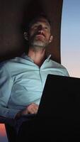 uma focado e dedicada profissional acionado dentro trabalhos às crepúsculo usando uma computador portátil para tarefas video