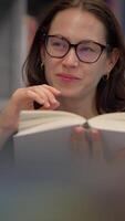 ein froh Leser Wer ist tief vertieft im ein interessant Buch beim das Bibliothek Rahmen video