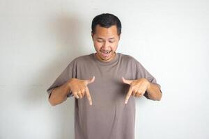 Young Adult Asian men pointing finger to the bottom or down with smiling face and exited expression with isolated white background photo