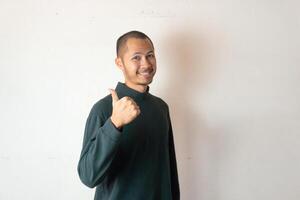 Young men wearing winter clothes smiling with thumbs up on isolated white background photo