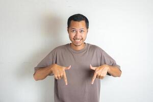 Young Adult Asian men pointing finger to the bottom or down with smiling face and exited expression with isolated white background photo