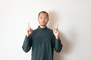 Young men wearing winter clothes is pointing with finger index up on isolated white background photo