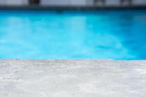 Empty grey ceramic table top and blurred swimming pool in tropical resort in summer banner background photo