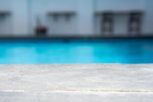 Empty grey ceramic table top and blurred swimming pool in tropical resort in summer banner background photo