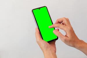 women hand holding smart mobile phone with blank green screen on isolated white background photo