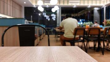 Blurry background of restaurant with wooden table in front for displaying product photo