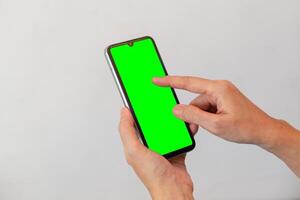women hand holding smart mobile phone with blank green screen on isolated white background photo