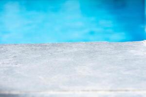 Empty grey ceramic table top and blurred swimming pool in tropical resort in summer banner background photo