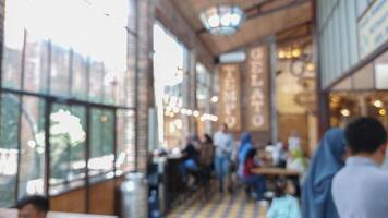Blurry background of restaurant with light bulb hanging and large window. Customer is paying the bill in cashier photo