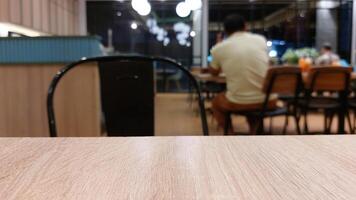 Blurry background of restaurant with wooden table in front for displaying product photo