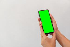 women hand holding smart mobile phone with blank green screen on isolated white background photo
