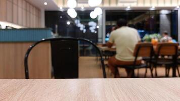 Blurry background of restaurant with wooden table in front for displaying product photo