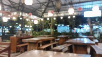 Blurry background of empty restaurant with light bulb and wooden table and wooden chair photo