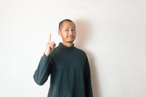Young men wearing winter clothes is pointing with finger index up on isolated white background photo