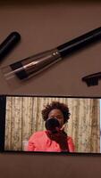 A woman is skillfully styling her hair using various tools while demonstrating on a mobile screen video