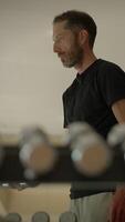 An individual who is fully focused and dedicated in a fitness setting while using weights video