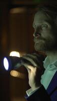 A man holding a flashlight stands in a dimly lit environment, creating an eerie atmosphere video