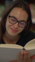 une femme profondément absorbé dans en train de lire une livre tandis que séance tranquillement dans une bibliothèque réglage video