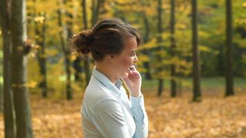 Woman talking on phone. Attractive woman talking on phone in autumn park video