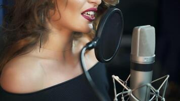 Jeune fille en chantant dans une microphone dans une studio. fermer de une chanteuse. video