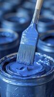 Paintbrush dripping with thick blue paint over open can photo