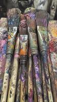 Set of dirty paint brushes covered in colorful paint lying on wood surface photo