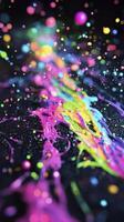 Neon paint splashing on black glittery surface photo