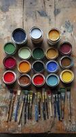 Paint cans forming a colorful palette with paintbrushes on a wooden table photo